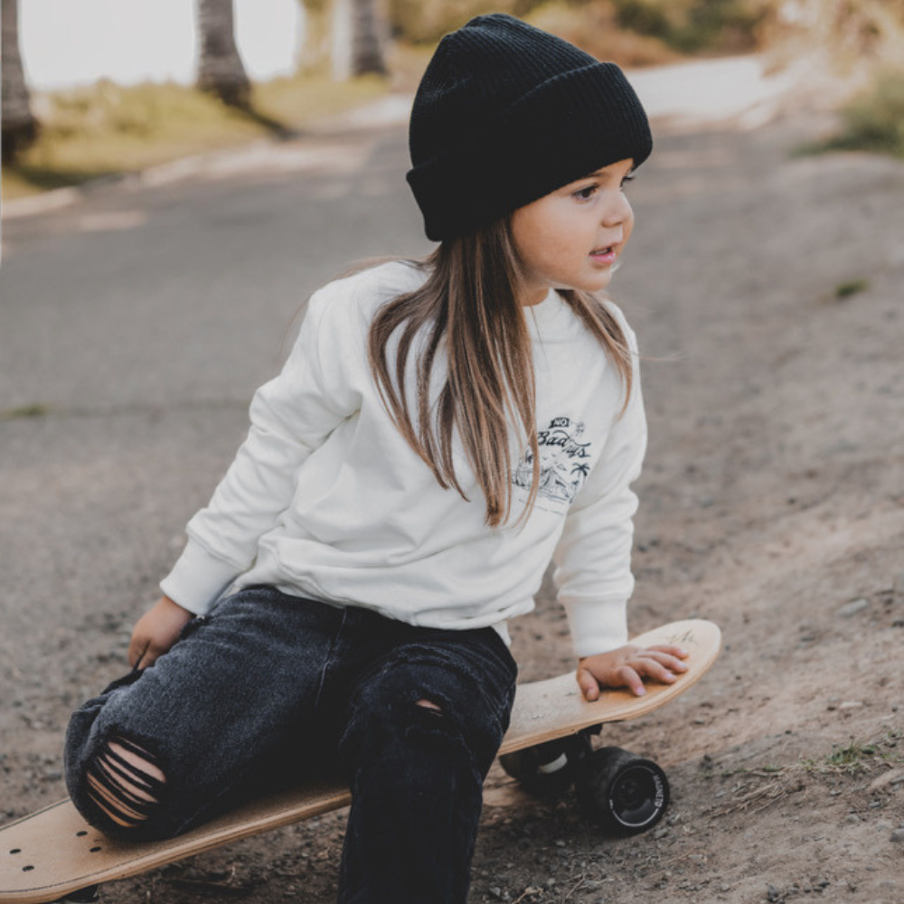 Knuckleheads Off-White Infant Crew Neck for kids, surf-inspired design in lightweight, breathable 100% cotton fabric, displayed against a laid-back, coastal-themed background. Available in sizes from 12 months to 8 years, this top is perfect for casual playdates, beach days, or park outings. Shown with durable, easy-to-wash fabric for stylish, everyday comfort.