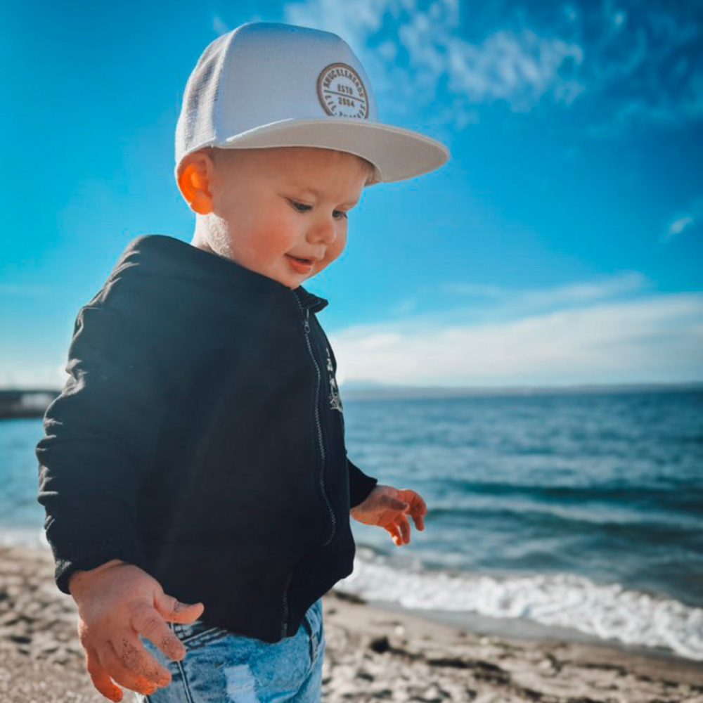 Hawaii Off White Snapback hat for infants and toddlers, crafted from 100% cotton for soft, comfortable wear. Features a medium-profile, structured 5-panel crown with a flat bill and adjustable snapback closure for a perfect fit as they grow. Embroidered tan Knuckleheads patch adds a stylish touch, ideal for little adventurers