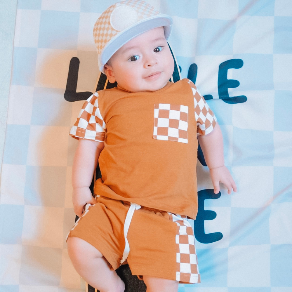 Image of White Kids Trucker Hat with Knuckleheads Patch and Checkered Pattern: A hip and stylish trucker hat designed for kids. The hat comes in crisp white and features a fashionable Knuckleheads patch adorned with a cool checkered pattern. Made with no sun mesh for a comfortable and breathable wear. Perfect accessory to elevate your child's style while providing sun protection.