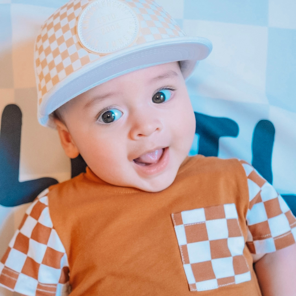 Image of White Kids Trucker Hat with Knuckleheads Patch and Checkered Pattern: A hip and stylish trucker hat designed for kids. The hat comes in crisp white and features a fashionable Knuckleheads patch adorned with a cool checkered pattern. Made with no sun mesh for a comfortable and breathable wear. Perfect accessory to elevate your child's style while providing sun protection.