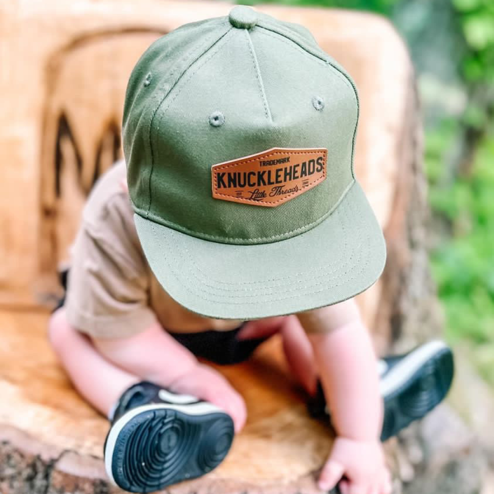 Image of Green Kids Trucker Hat with Knuckleheads Patch: A vibrant and stylish accessory designed for kids. In a lively green hue, it showcases a striking Knuckleheads patch on the front. Elevate your child's style with this fashionable hat, perfect for adding a pop of color to their outfits. Crafted with care, this green kids trucker hat with the Knuckleheads patch is a must-have addition to their wardrobe, suitable for various occasions and everyday wear.