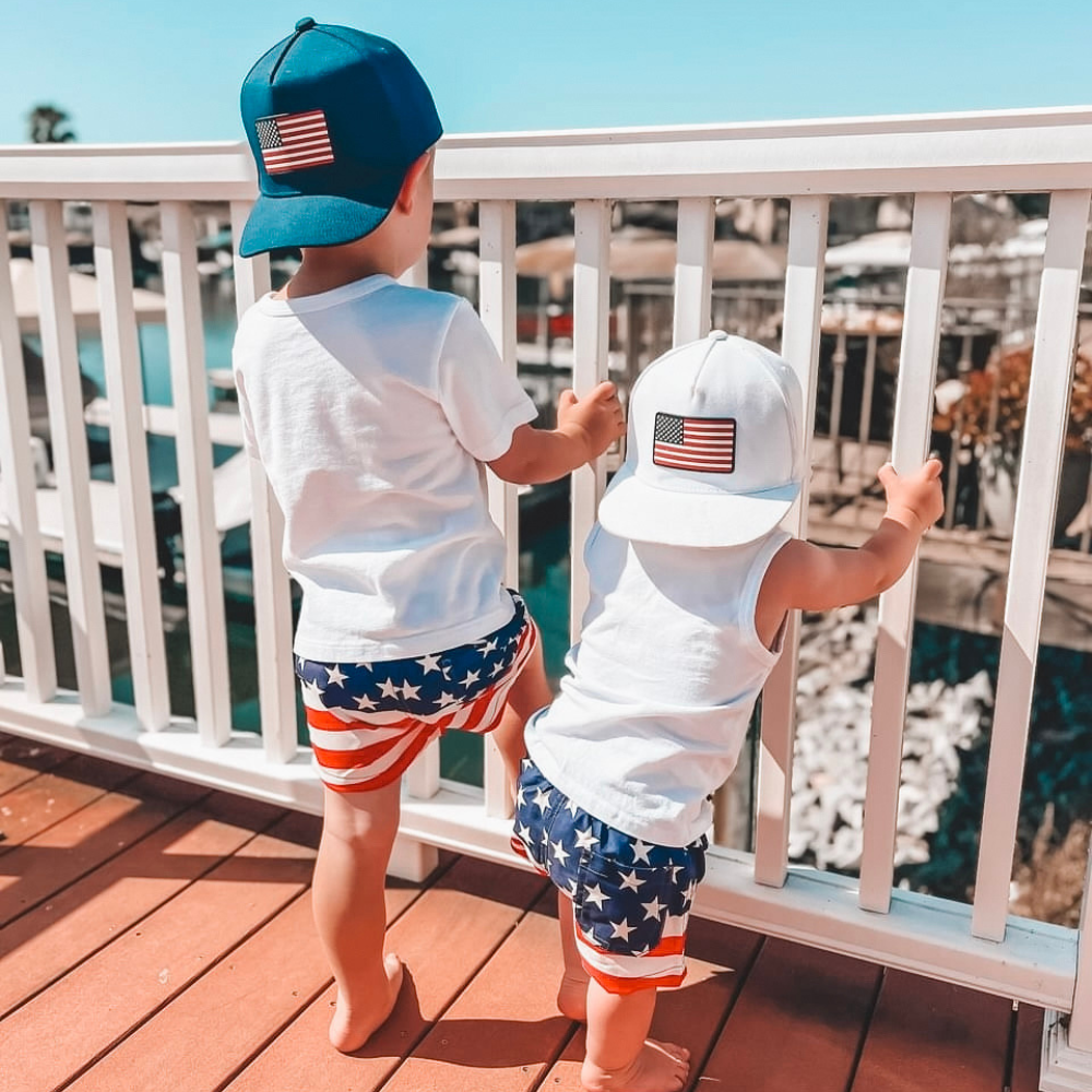 Image of Navy USA Kids Trucker Hat with USA Flag Patch: A patriotic and stylish trucker hat designed for kids. The hat comes in classic navy blue, showcasing a striking USA flag patch on the front. Perfect for young patriots to show their American pride while staying cool and comfortable. Elevate your child's style with this trendy and functional accessory, ideal for outdoor adventures and everyday wear.