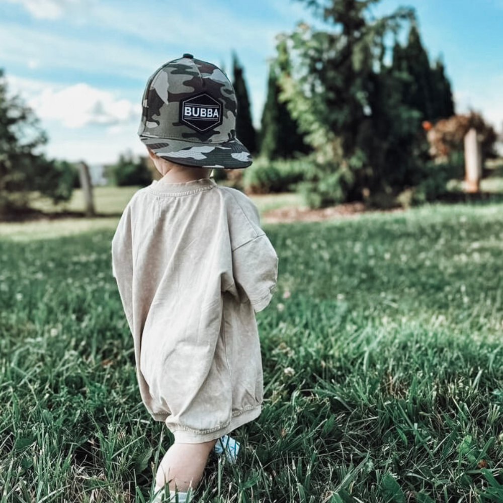 Image of Camo Kids Trucker Hat with 'Bubba' Patch: A cool and adventurous trucker hat designed for kids. The hat features a stylish camo print, complemented by a charming 'Bubba' patch on the front. Elevate your child's style with this trendy and fun accessory, perfect for outdoor explorations and everyday wear. Crafted with comfort in mind, this camo trucker hat is a must-have addition to their wardrobe.