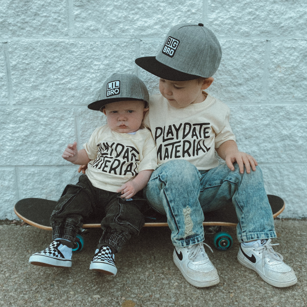 Models wearing Kids Trucker Hats featuring 'Lil Bro' and 'Big Bro' patches. These playful and endearing hats are designed for children, showcasing charming patches that highlight sibling connection. A standout accessory for little ones to express their unique style and special bond.