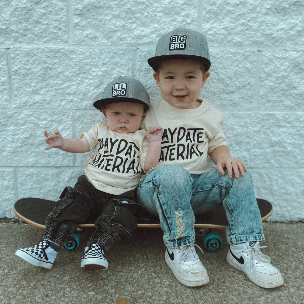 Models wearing Kids Trucker Hats featuring 'Lil Bro' and 'Big Bro' patches. These playful and endearing hats are designed for children, showcasing charming patches that highlight sibling connection. A standout accessory for little ones to express their unique style and special bond.