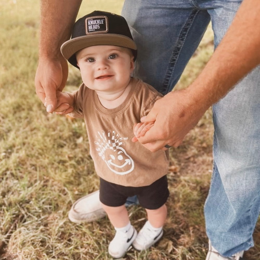 Image of Tan Kids T-Shirt with Knuckleheads Logo: A stylish and versatile addition to kids' wardrobes. This tan-colored t-shirt features the iconic Knuckleheads logo on the front. Keep your child's style on point with this comfortable shirt, perfect for adding a touch of character to their outfits.