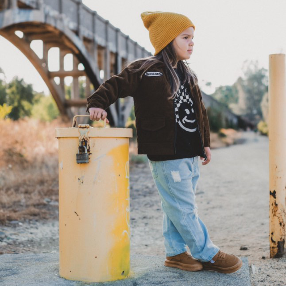 Image highlighting a vibrant yellow beanie from Knuckleheads, designed for children. This versatile beanie, complete with the Knuckleheads brand tag, offers a classic style suitable for infants and toddlers. A cheerful addition to the collection of Infant hats, adding a bright touch of charm.