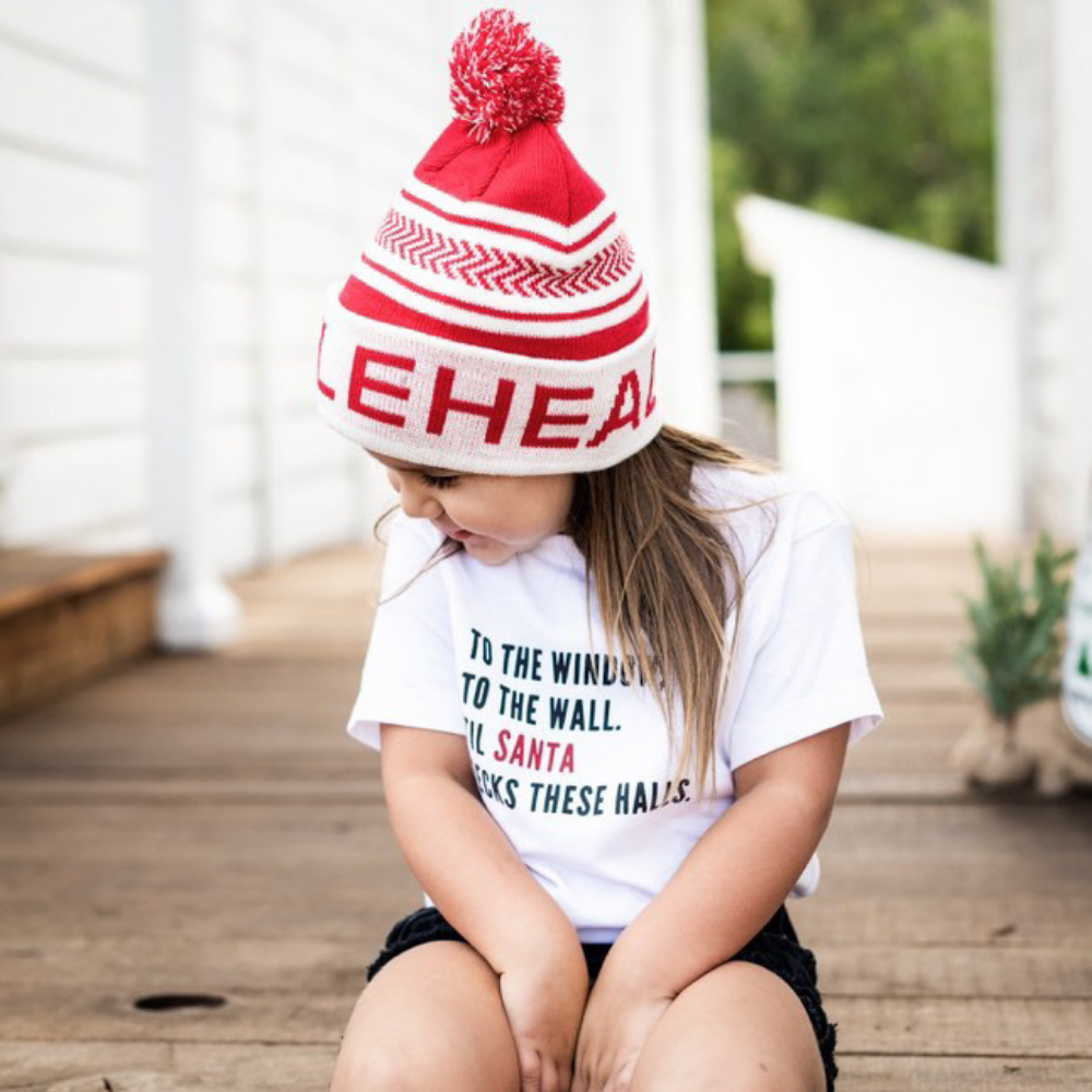 Image displaying a red and white fold-up beanie with a pom from Knuckleheads, designed for children. This versatile beanie combines a classic style with the Knuckleheads brand tag, perfect for infants and toddlers. A playful addition to the collection of Infant hats, enhancing its charm.