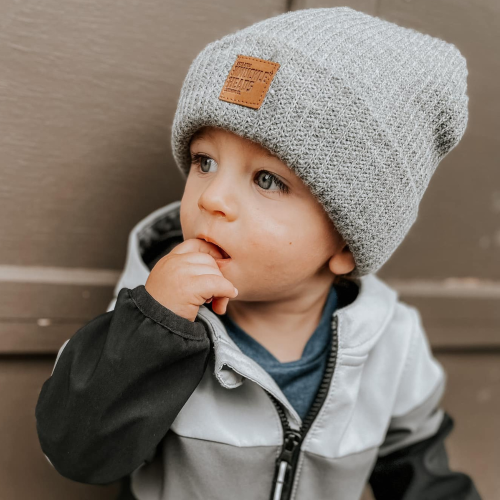 child wearing a gray beanie with patch